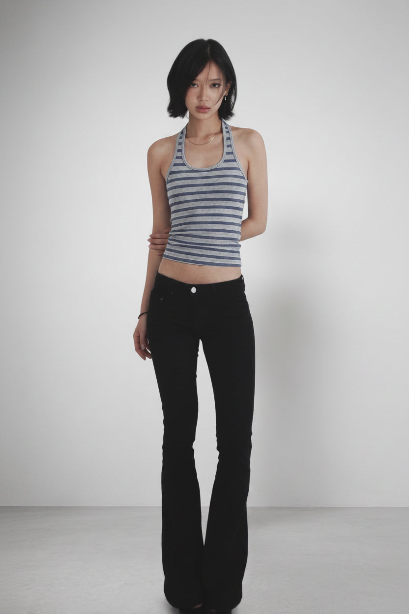 Woman wearing a striped tank top and black flared pants on a white background