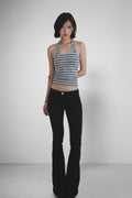 Woman wearing a striped tank top and black flared pants on a white background